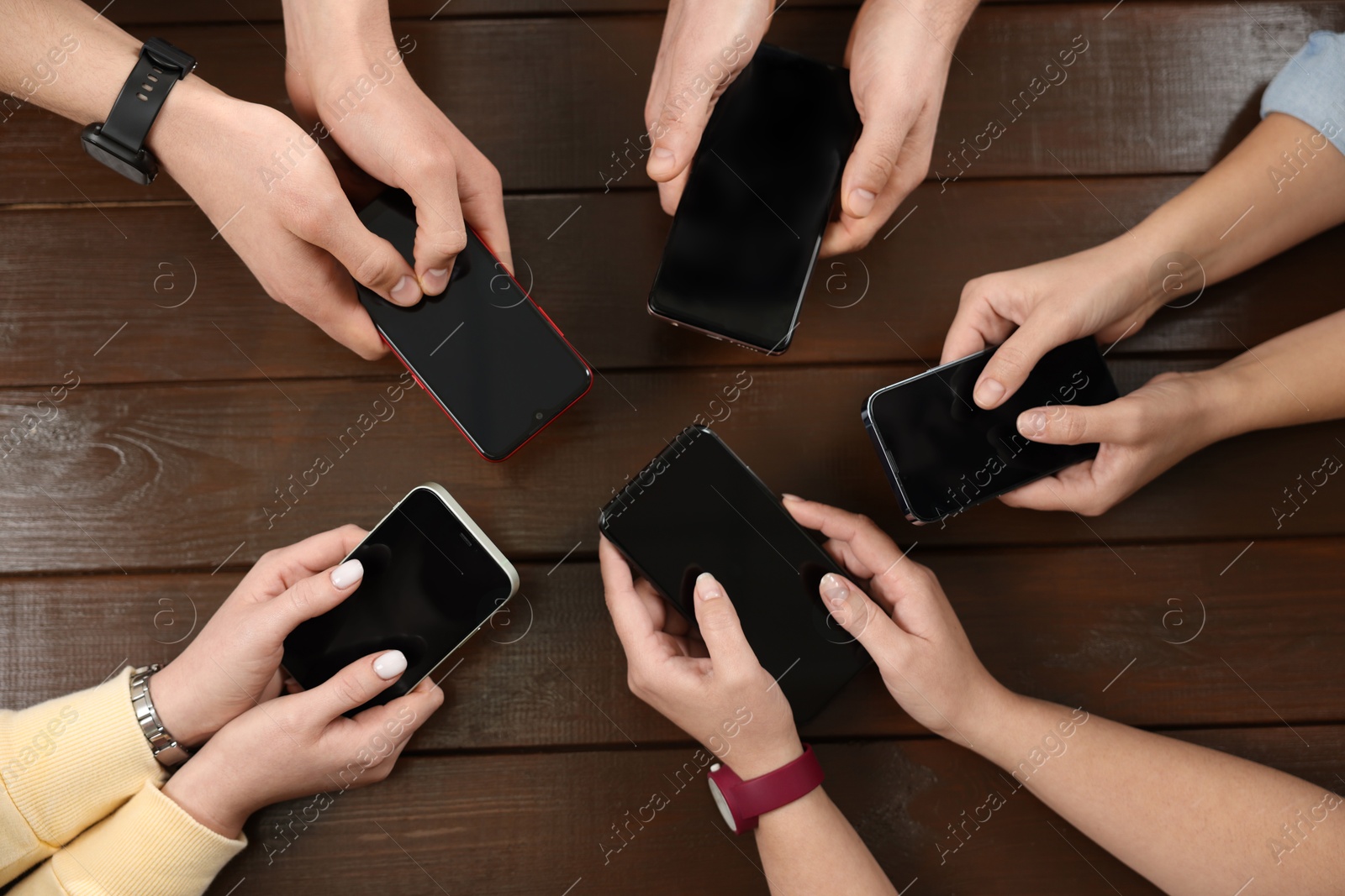 Photo of Internet addiction. People with smartphones at wooden table, top view