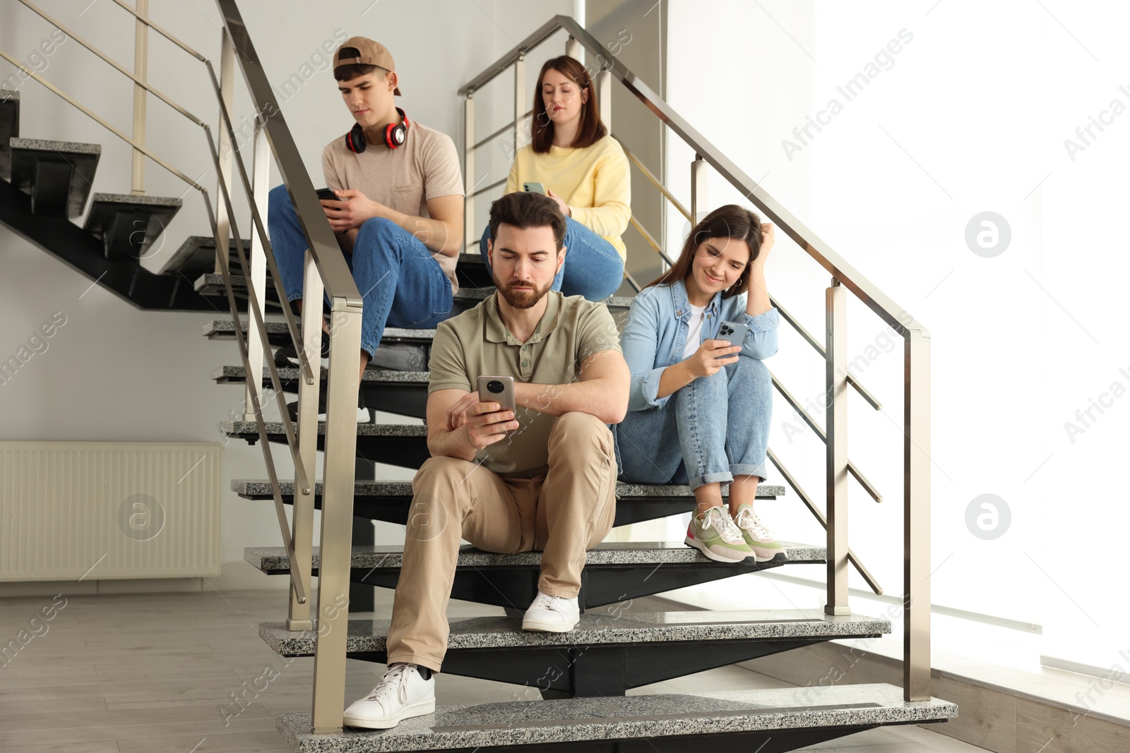 Photo of Internet addiction. Group of people with smartphones on stairs indoors