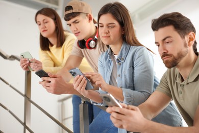 Photo of Internet addiction. Group of people with smartphones on stairs indoors