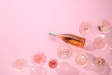 Photo of Delicious rose wine in glasses and bottle on pink background, flat lay. Space for text