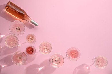 Photo of Delicious rose wine in glasses and bottle on pink background, flat lay. Space for text