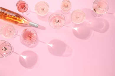 Photo of Delicious rose wine in glasses and bottle on pink background, flat lay. Space for text