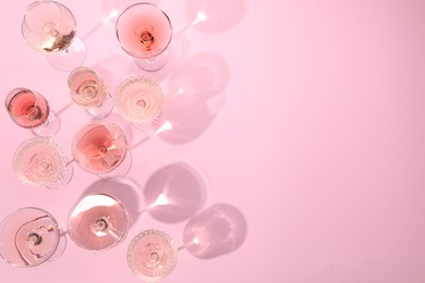 Photo of Delicious rose wine in glasses on pink background, flat lay. Space for text