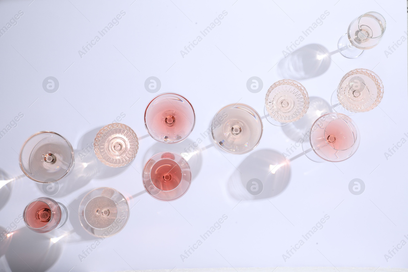 Photo of Delicious rose wine in glasses on white background, flat lay. Space for text