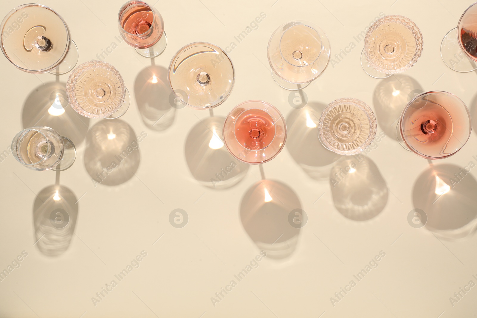 Photo of Delicious rose wine in glasses on beige background, flat lay. Space for text