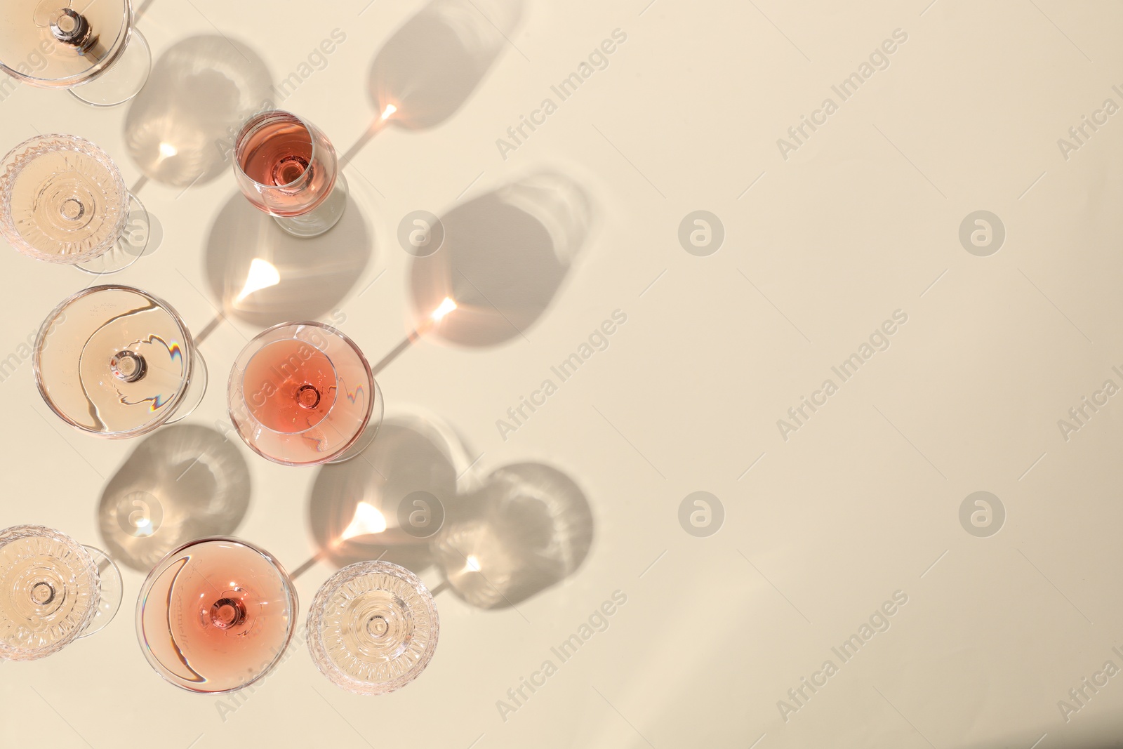 Photo of Delicious rose wine in glasses on beige background, flat lay. Space for text