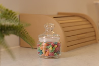 Photo of Gummy candies in glass jar on white table indoors