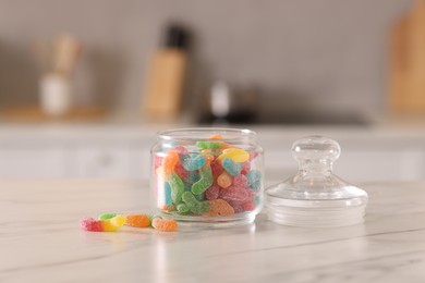 Photo of Gummy candies in glass jar on white marble table indoors