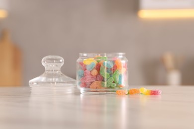 Photo of Gummy candies in glass jar on white marble table indoors