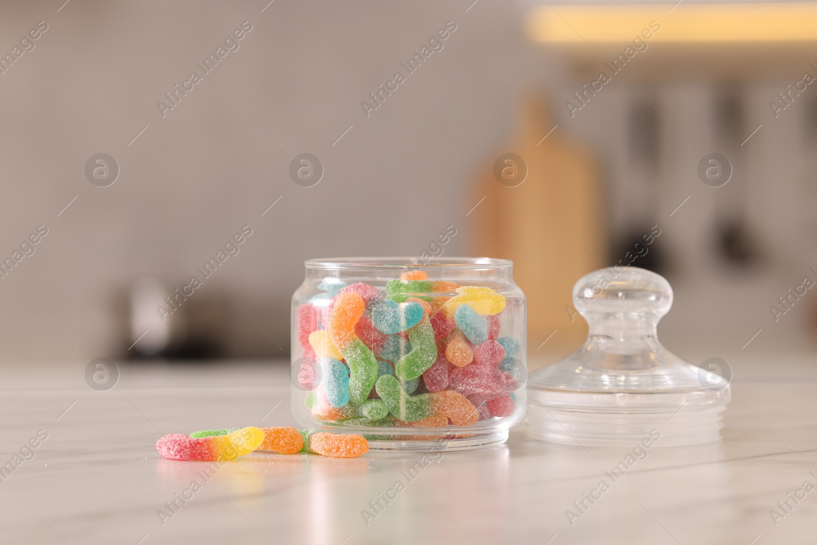 Photo of Gummy candies in glass jar on white marble table indoors