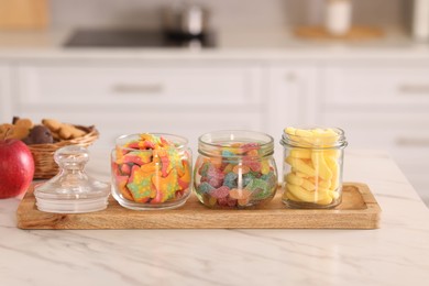 Photo of Tasty gummy candies and cookies on white marble table