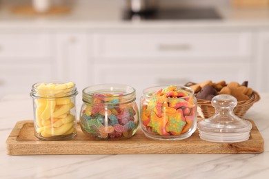 Photo of Tasty gummy candies and cookies on white marble table