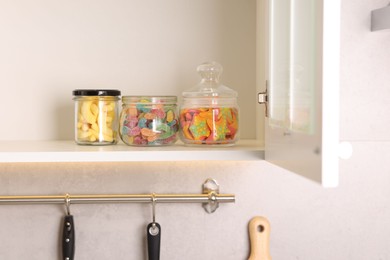 Photo of Tasty gummy candies in jars on shelf