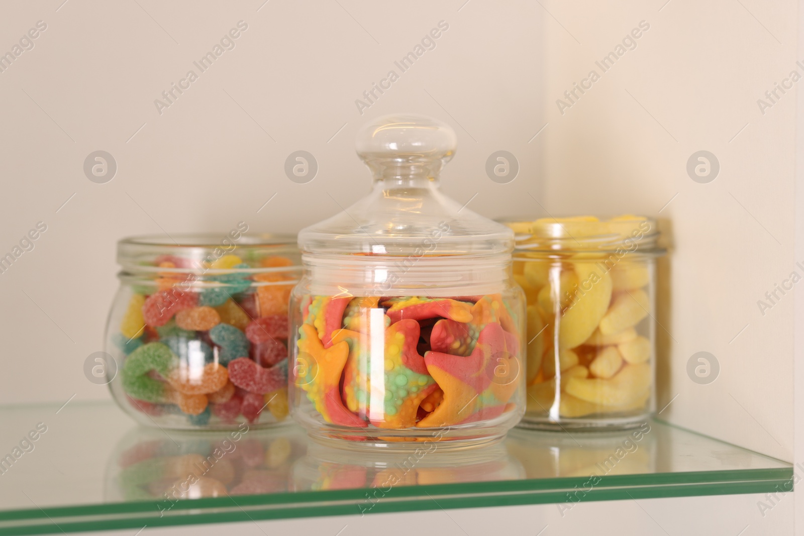 Photo of Tasty gummy candies in jars on shelf