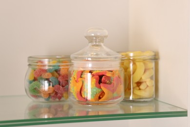 Photo of Tasty gummy candies in jars on shelf