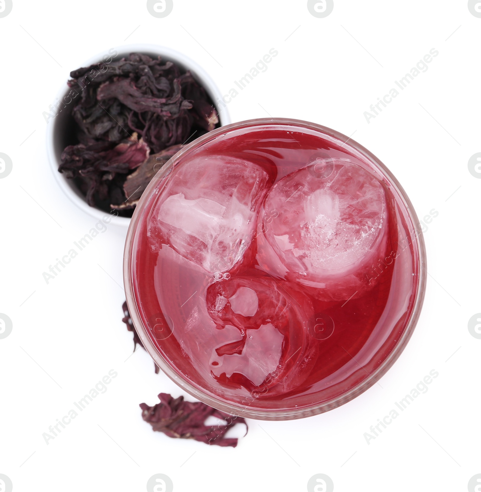 Photo of Delicious hibiscus tea with ice in glass and dry roselle sepals isolated on white, top view