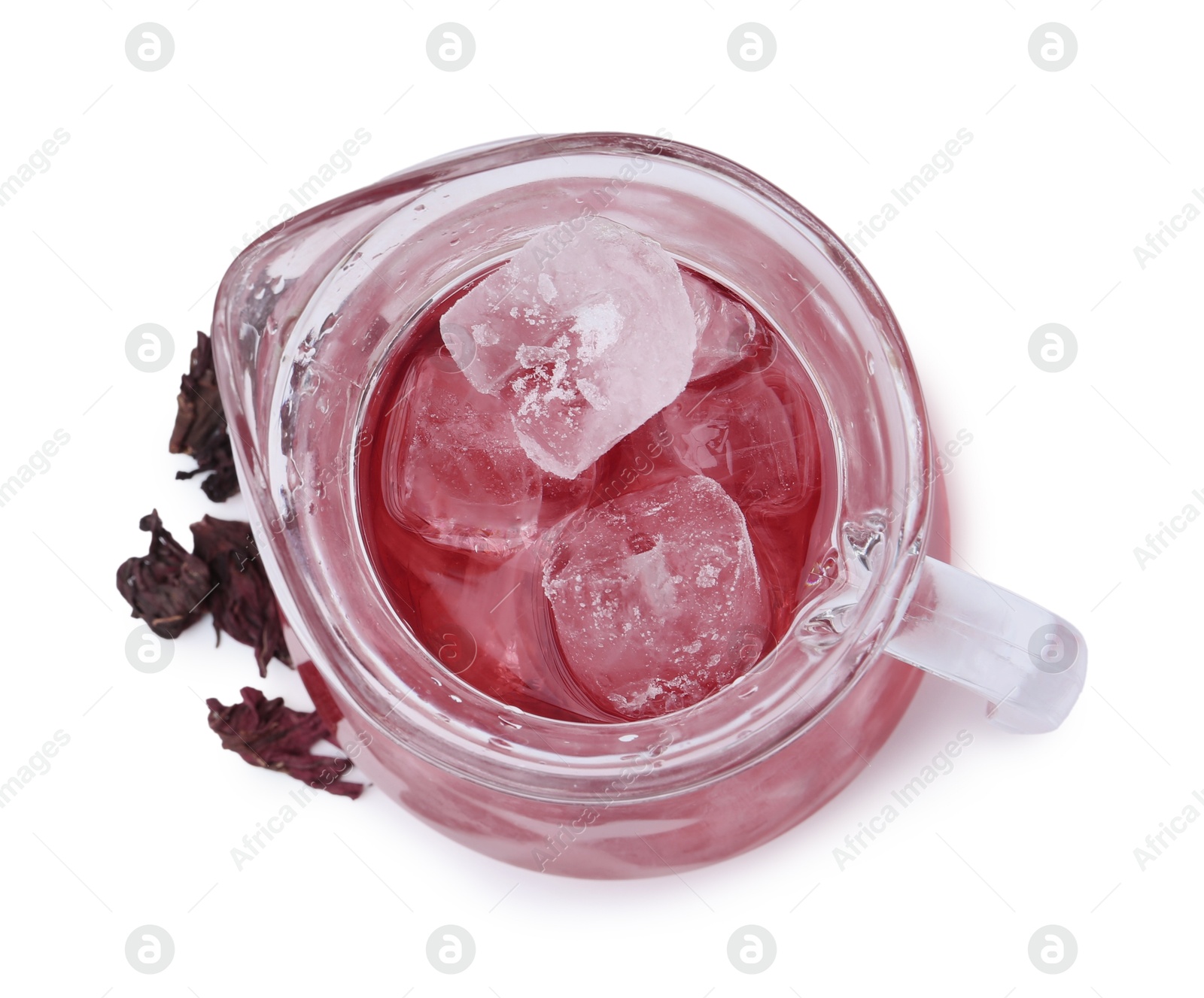 Photo of Delicious hibiscus tea with ice in glass jug and dry roselle sepals isolated on white, top view