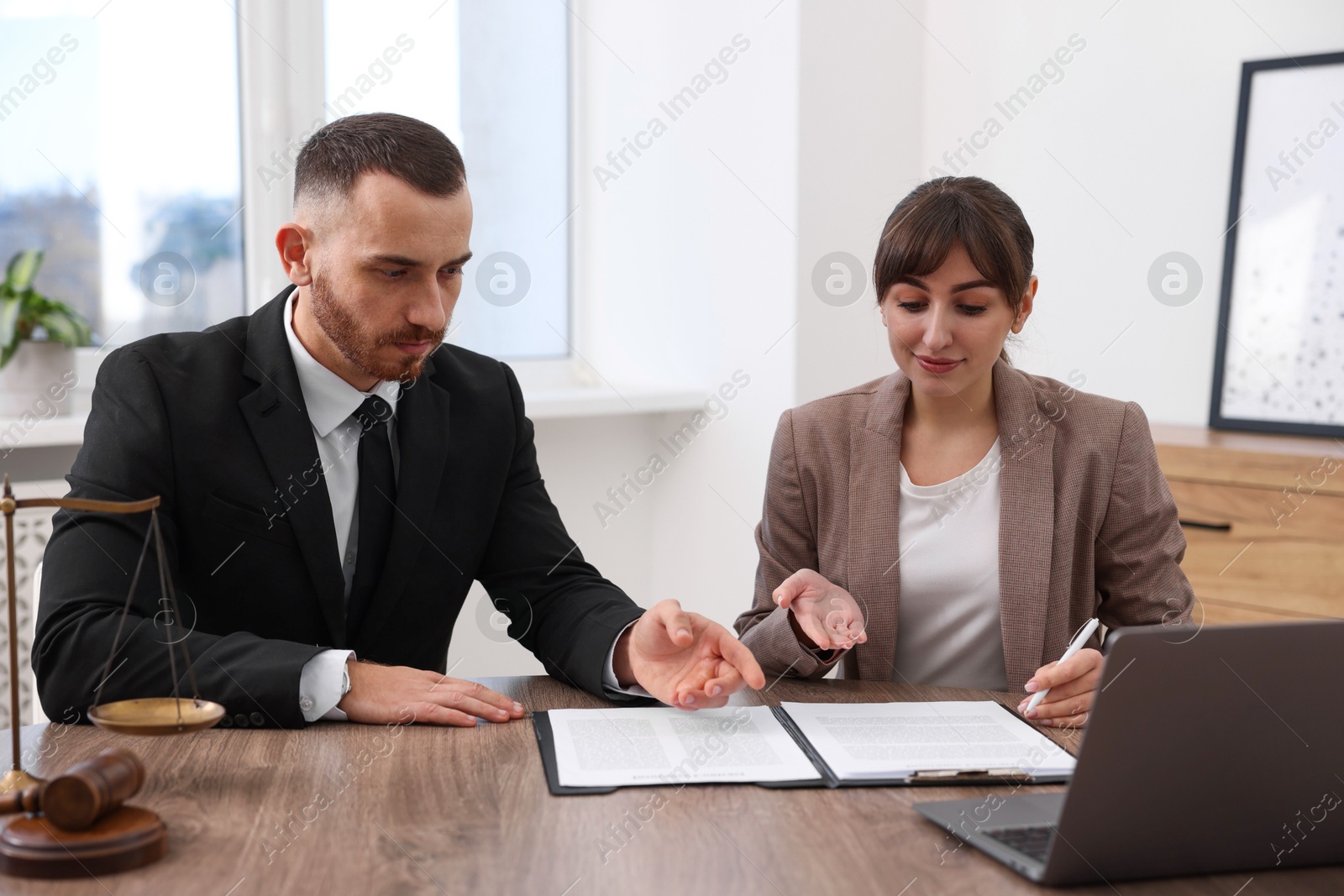 Photo of Man having meeting with professional notary at wooden desk indoors