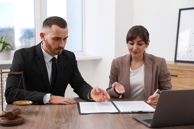 Photo of Man having meeting with professional notary at wooden desk indoors