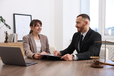 Client signing notarial paperwork during meeting with lawyer at wooden desk indoors