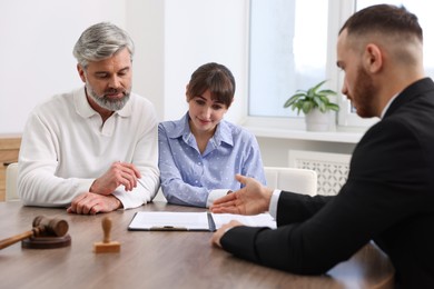 Couple having meeting with professional notary at wooden desk indoors