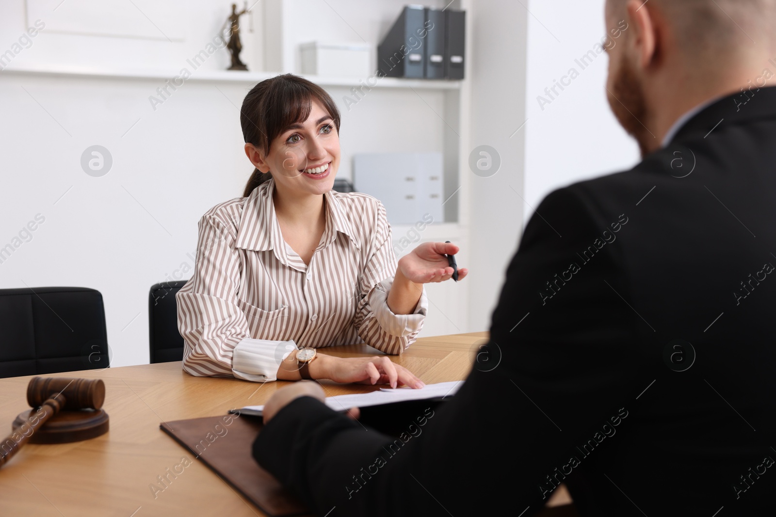 Photo of Woman having meeting with professional notary at wooden desk indoors