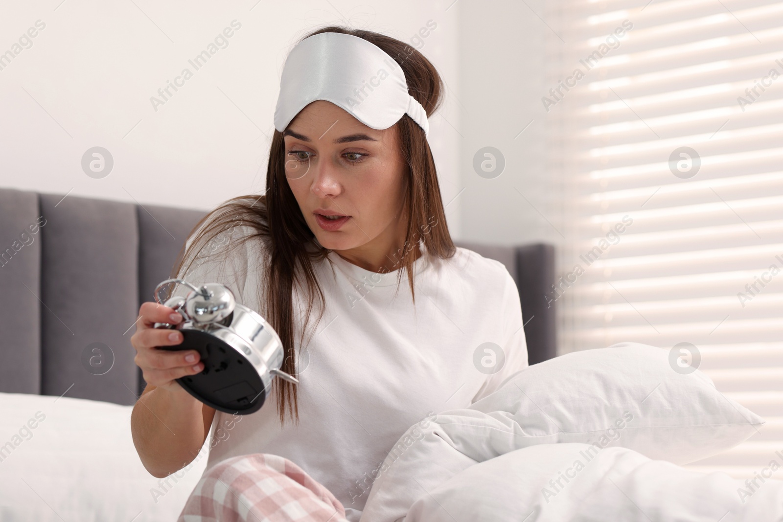 Photo of Overslept woman with alarm clock in bed at home