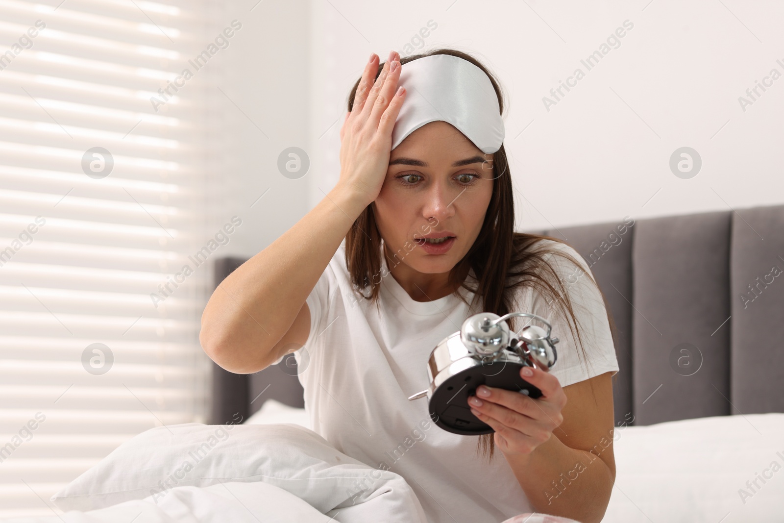 Photo of Overslept woman with alarm clock in bed at home