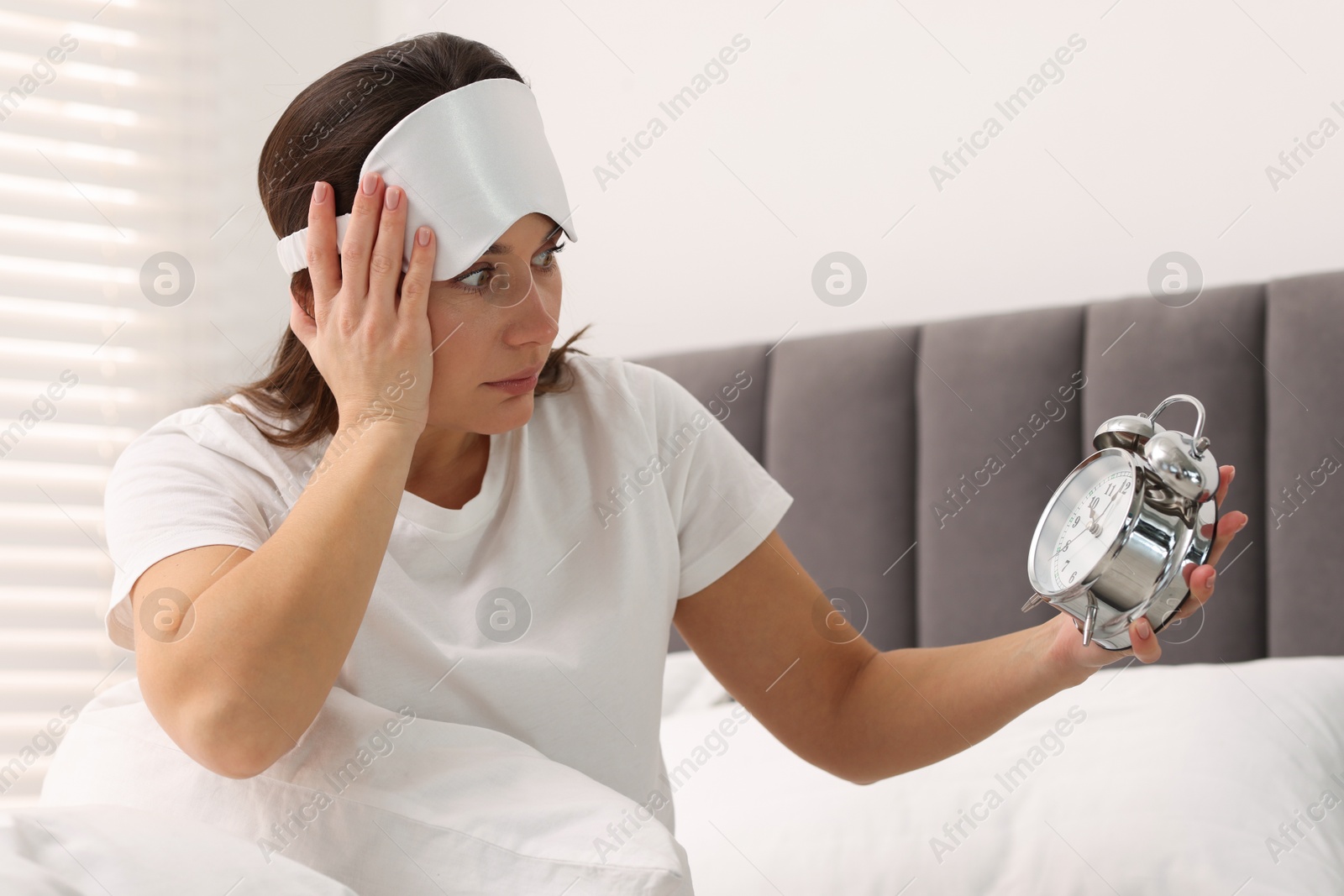 Photo of Overslept woman with alarm clock in bed at home