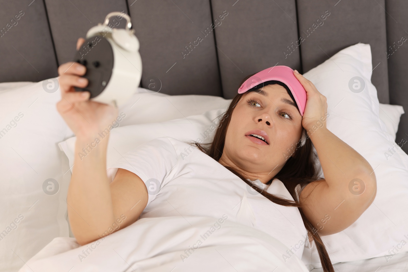 Photo of Overslept woman with alarm clock in bed at home