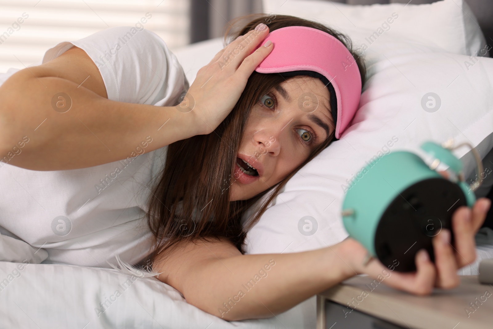 Photo of Overslept woman with alarm clock in bed at home