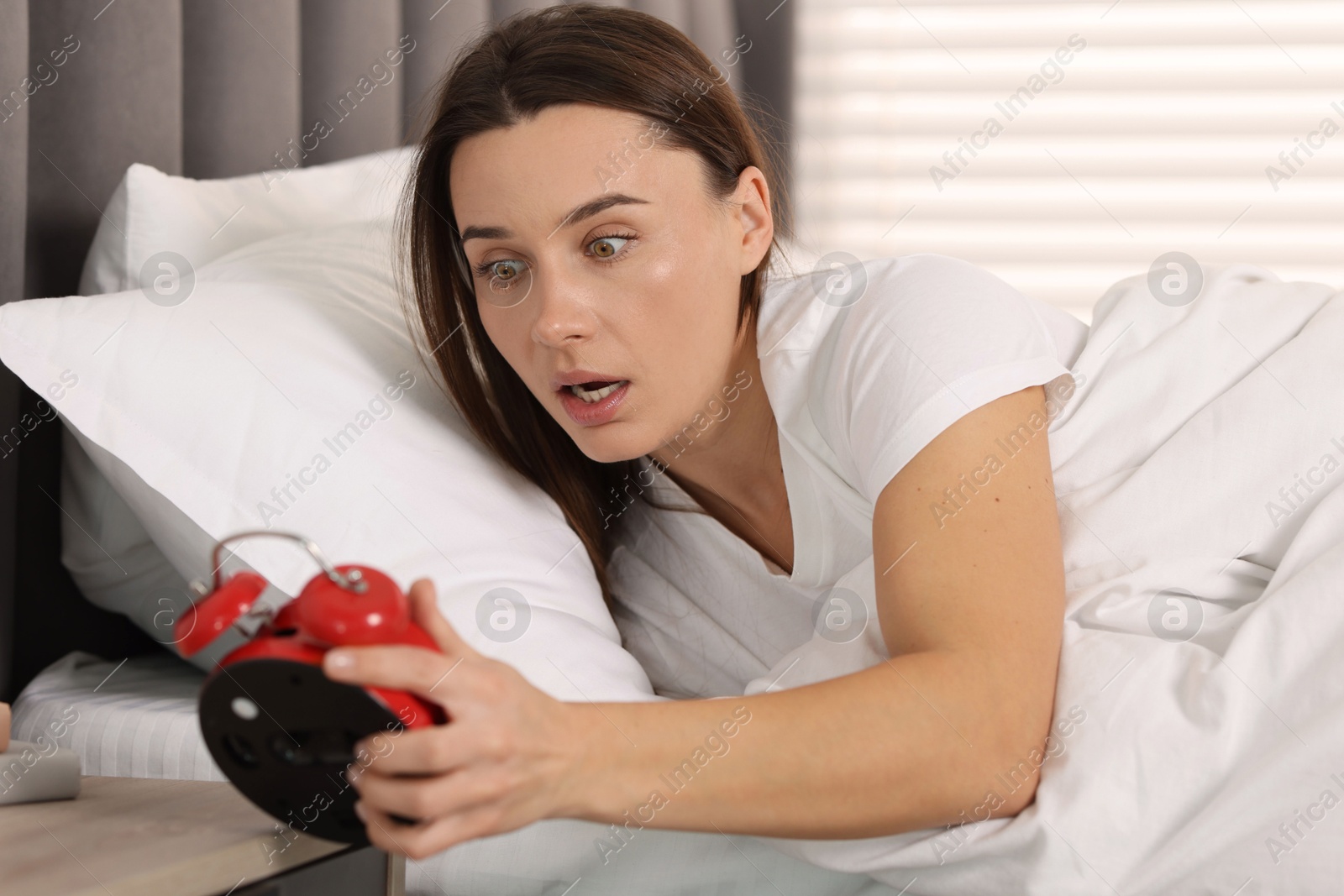 Photo of Overslept woman with alarm clock in bed at home