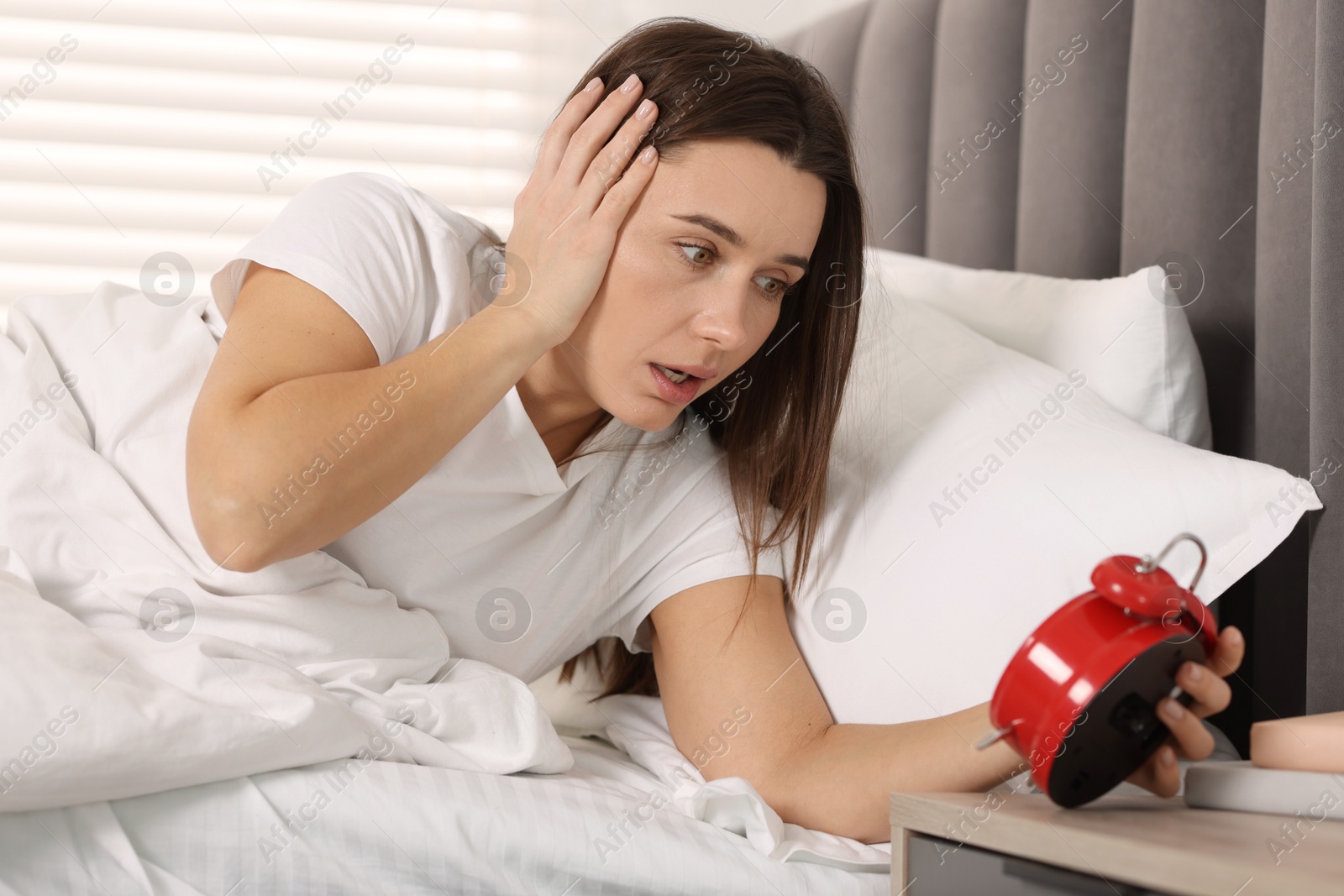 Photo of Overslept woman with alarm clock in bed at home