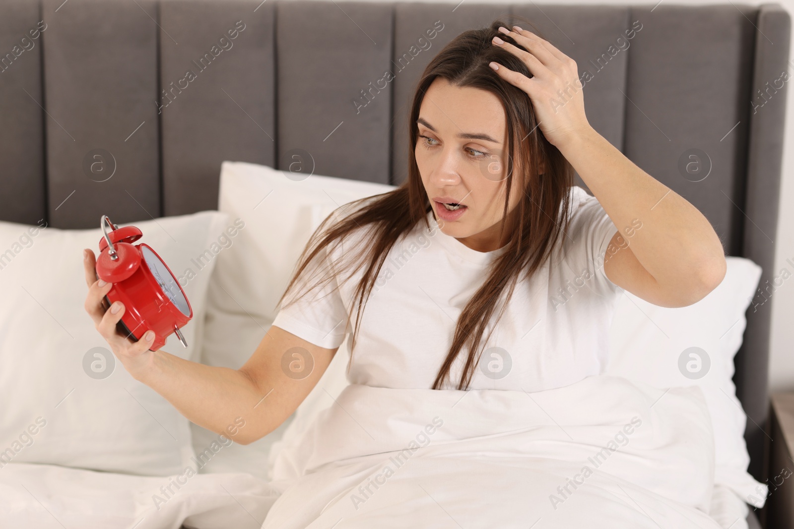 Photo of Overslept woman with alarm clock in bed at home