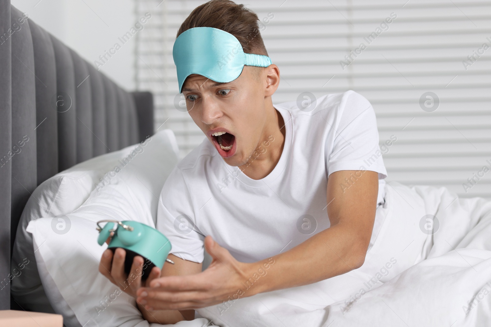 Photo of Overslept man with alarm clock in bed at home