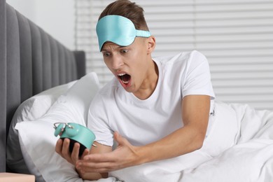 Photo of Overslept man with alarm clock in bed at home