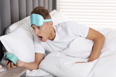 Photo of Overslept man with alarm clock in bed at home