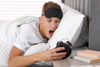 Photo of Overslept man with alarm clock in bed at home