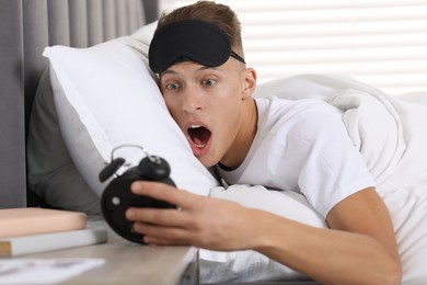 Photo of Overslept man with alarm clock in bed at home