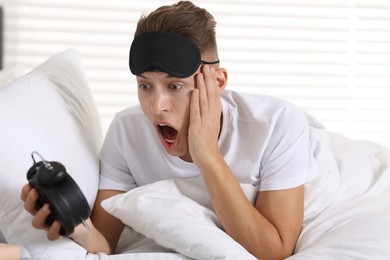 Photo of Overslept man with alarm clock in bed at home