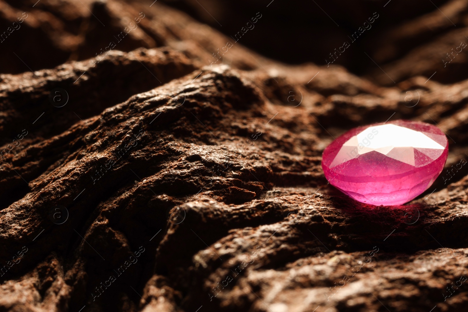 Photo of Beautiful shiny pink gemstone on stone, closeup. Space for text