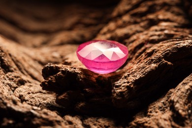 Photo of Beautiful shiny pink gemstone on stone, closeup