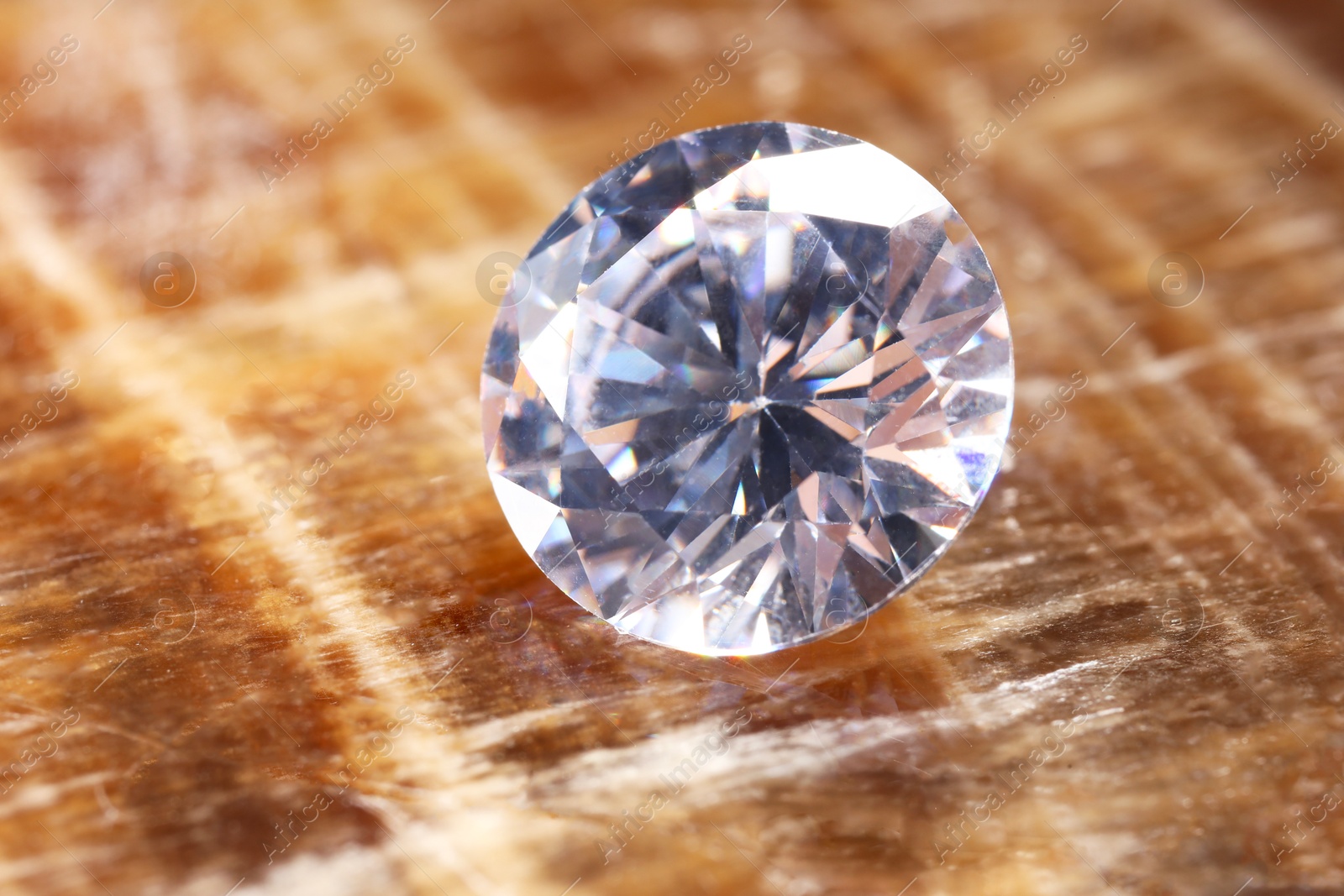 Photo of Beautiful shiny gemstone on brown marble surface, closeup