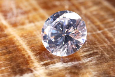 Photo of Beautiful shiny gemstone on brown marble surface, closeup