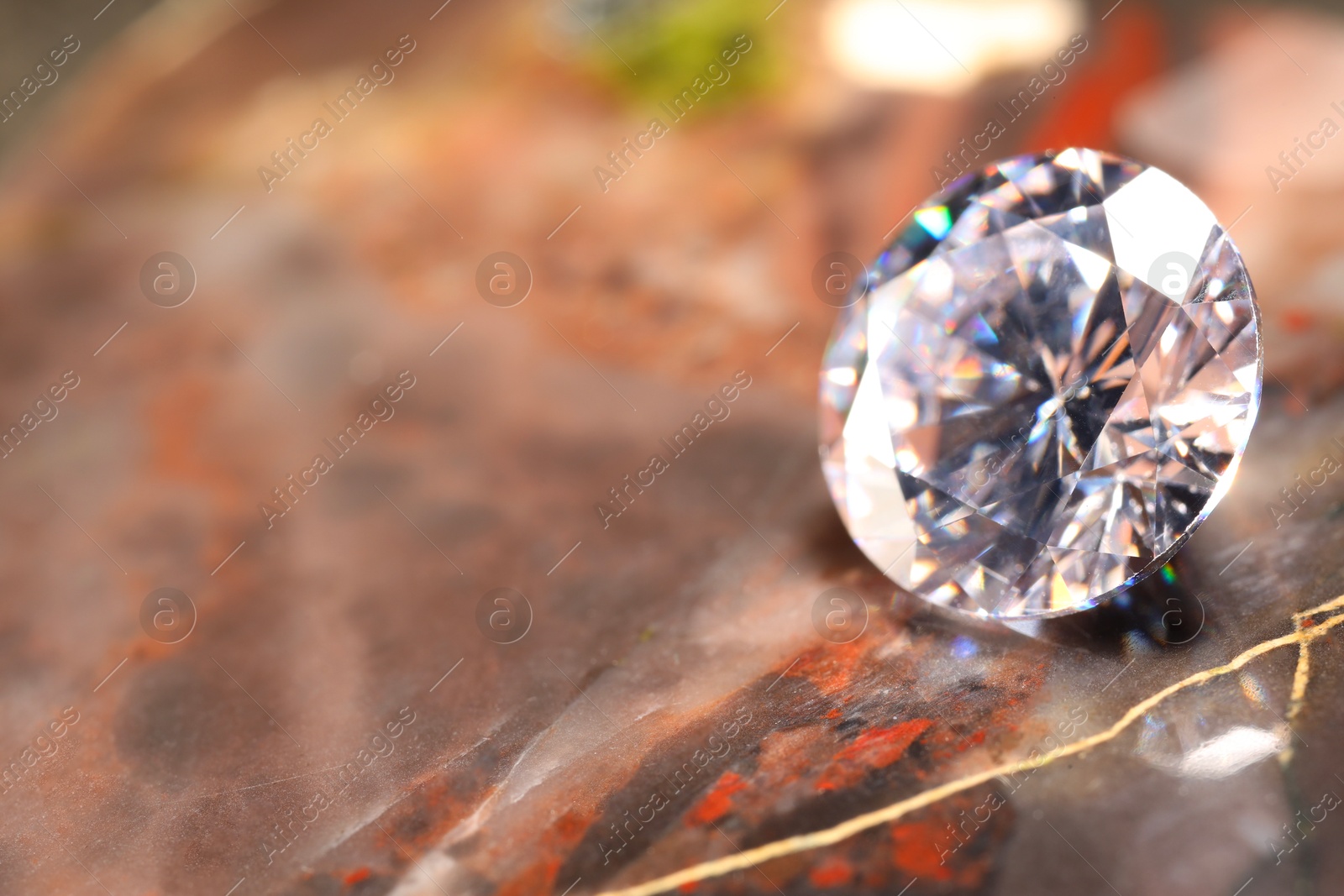 Photo of Beautiful shiny gemstone on brown marble surface, closeup. Space for text