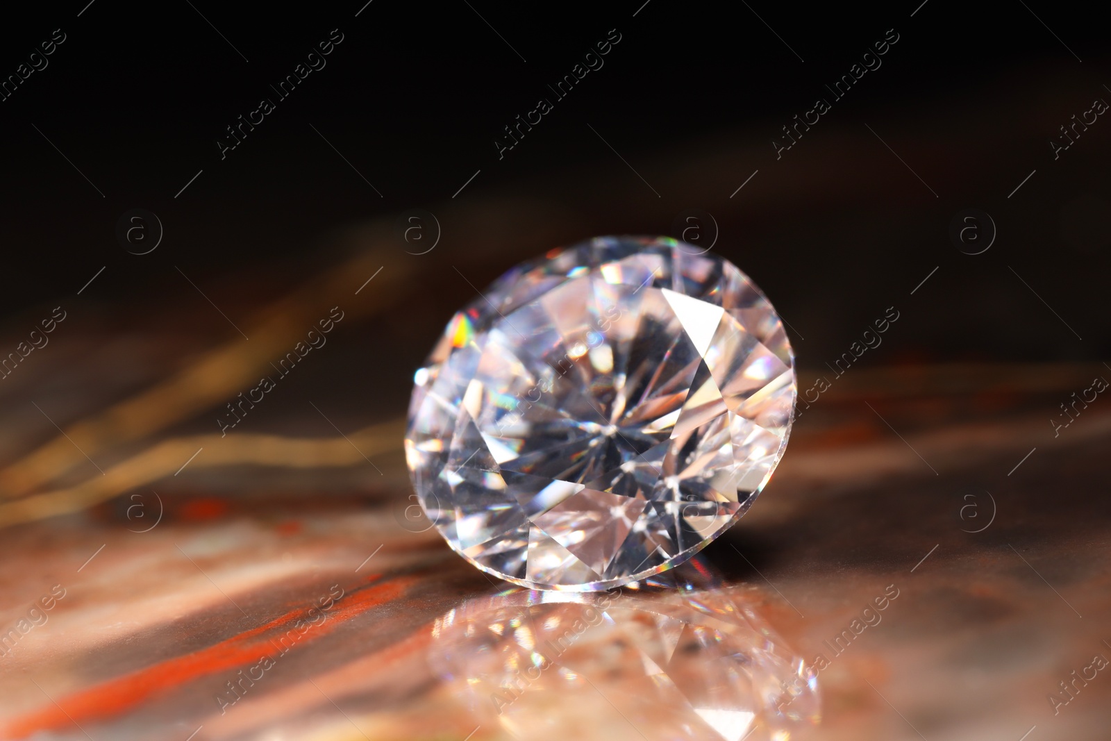 Photo of Beautiful shiny gemstone on brown marble surface, closeup