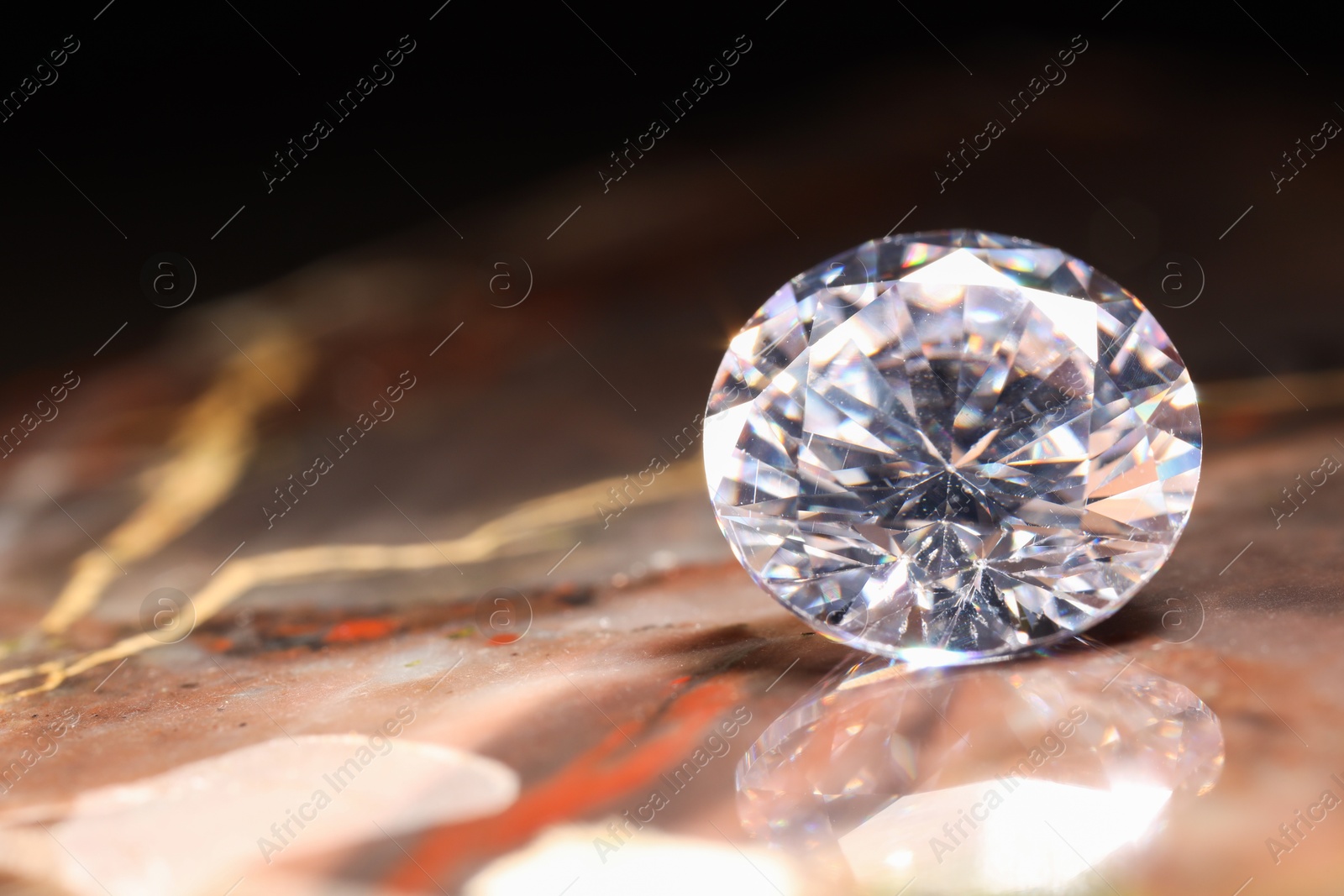 Photo of Beautiful shiny gemstone on brown marble surface, closeup. Space for text