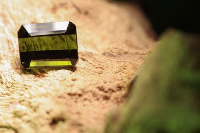 Photo of Beautiful shiny green gemstone on stone, space for text