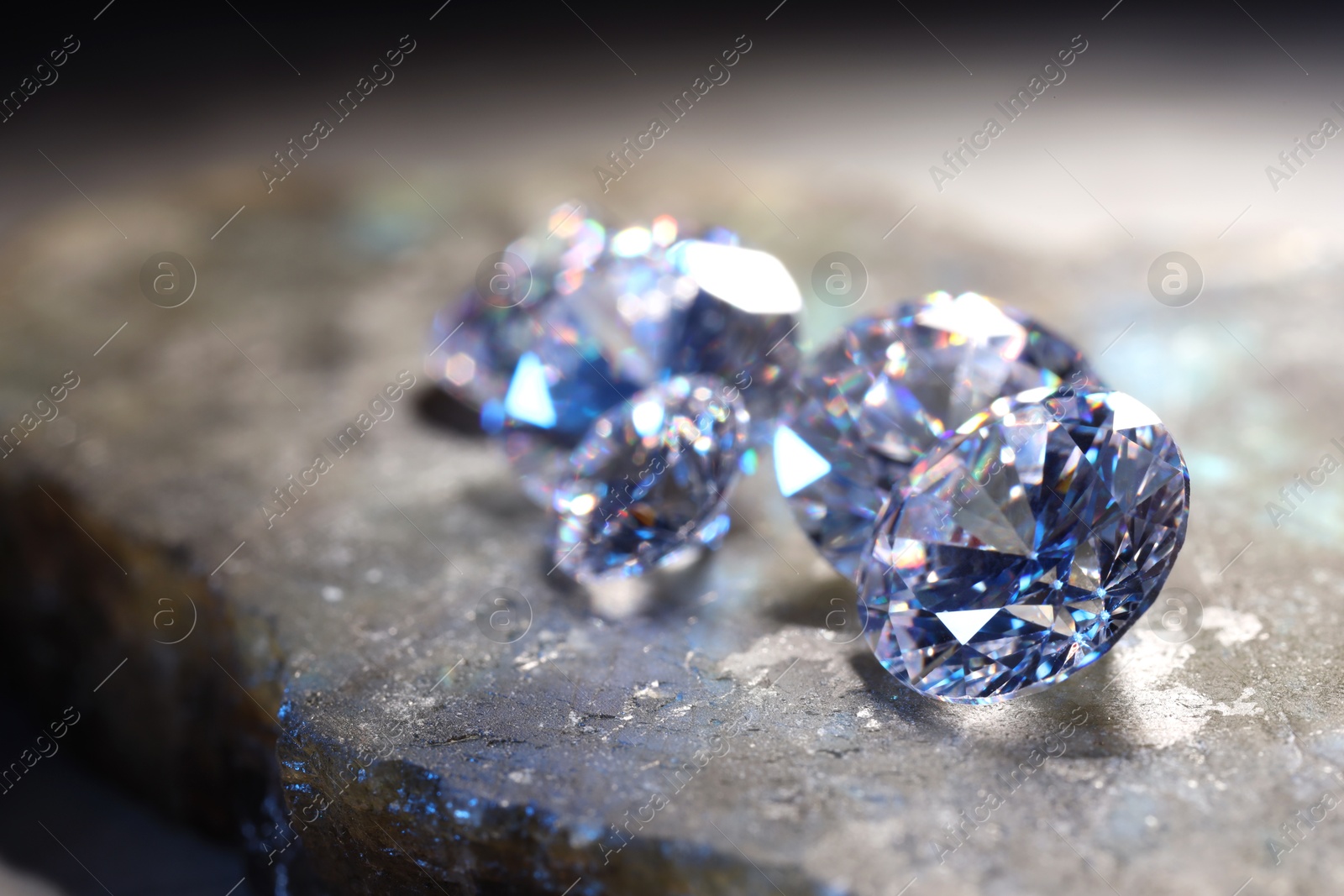 Photo of Beautiful shiny gemstones on stone, closeup view