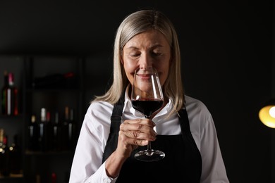 Photo of Professional sommelier tasting red wine in glass indoors